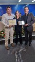 (à esq.) Ver Flávio Togni de Lima e Silva, proponente da homenagem e Ver. Marcelo Heitor da Silva, entregam placa e diploma à Sra Ana Paula Tranche, presidente da ADEFIP.