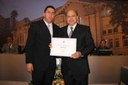 Ver. Flávio H. Faria entrega diploma ao Sr. Ildeu Pereira, diretor geral da TV Poços
